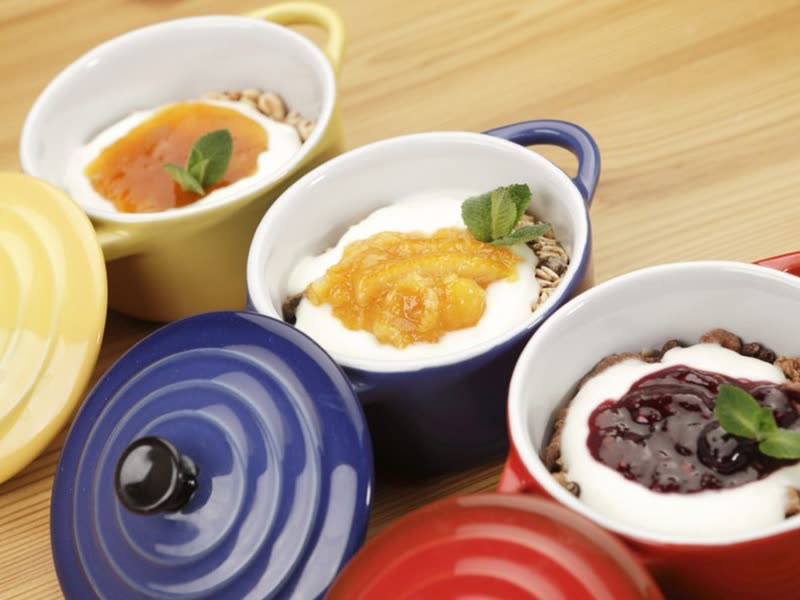 Three cocottes of natural yoghurt with muesli and jam