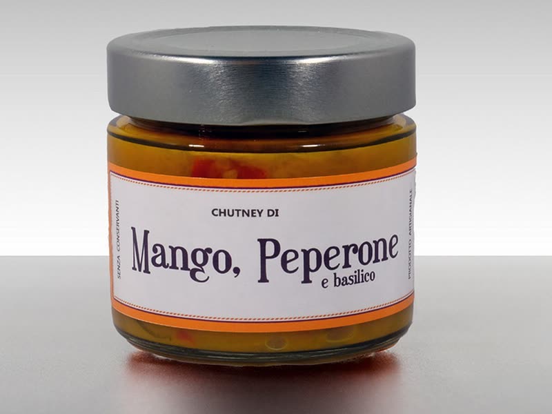 Jar of mango, red peppers and basil chutney on a grey background