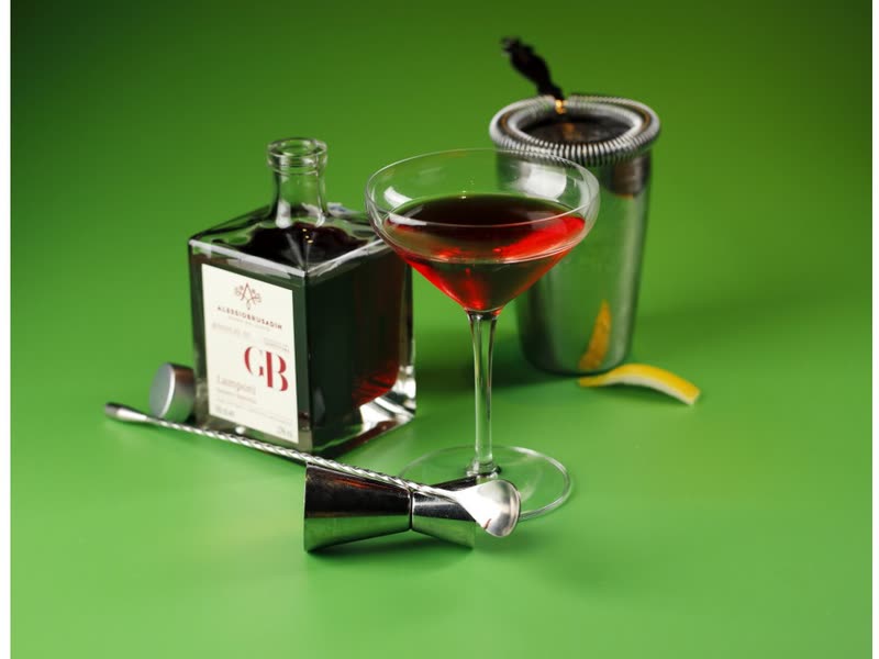 Kir Royale coupe next to the bottle of Rosolio GB on a green background