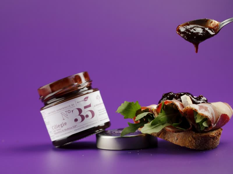 Jar N°35 of cherry chutney with a crostino and a dripping spoon